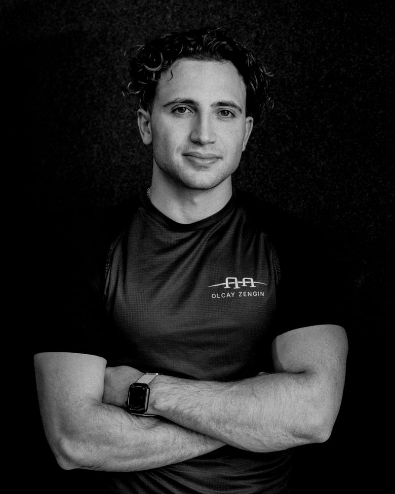 Olcay Zengin, Calisthenics-Coach, mit verschränkten Armen vor dunkler Wand